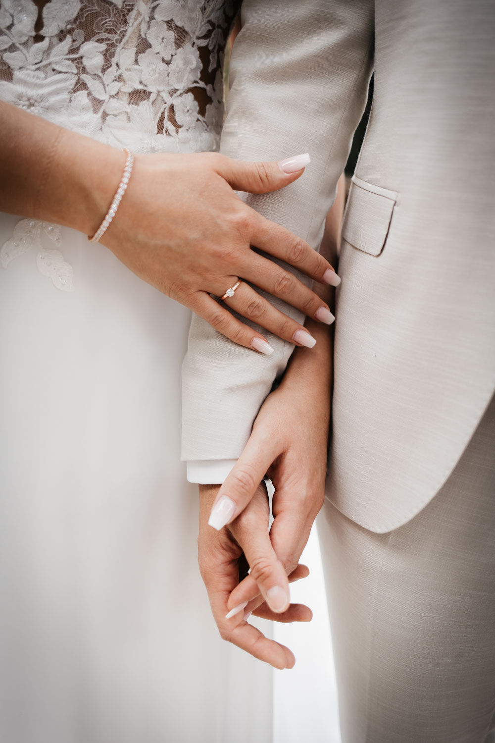 Hochzeitspaar steht nebeneinander und halten sich an den Händen