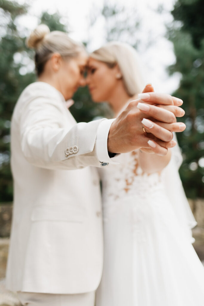 Hochzeitspaar hält sich die Hände, sie stehen Stirn an Stirn beieinander