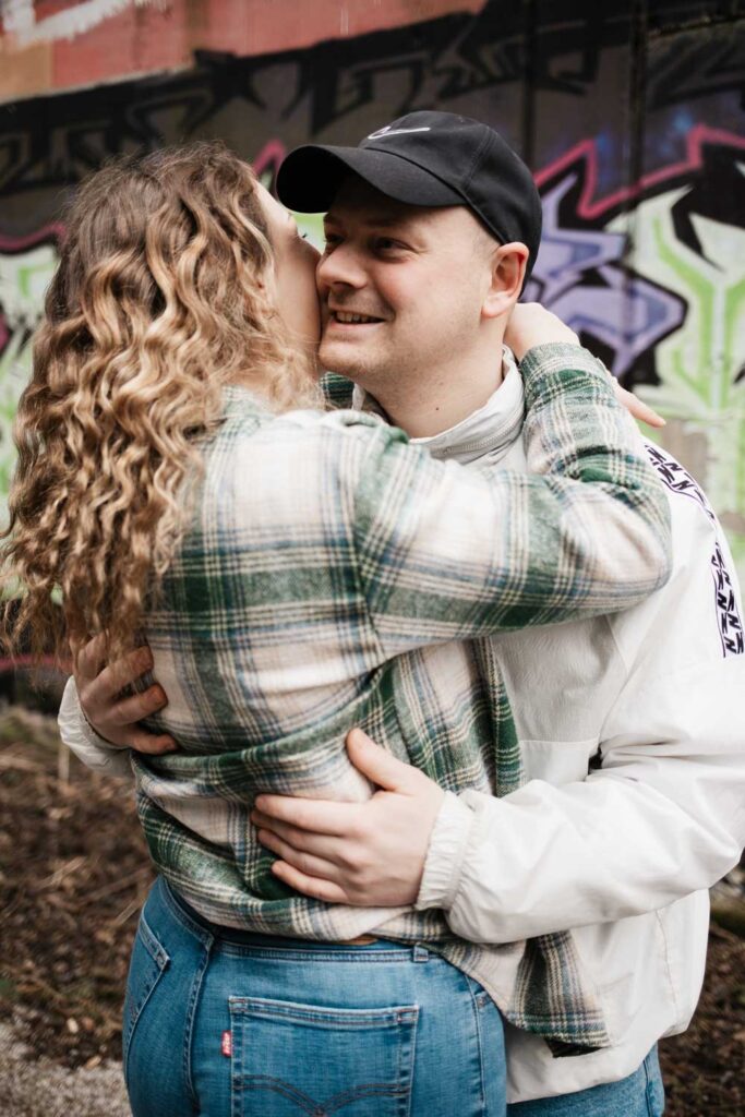 Paarshooting Phoenix West Dortmund Paar umarmt sich und die Freundin flüstert ihrem Freund etwas ins Ohr