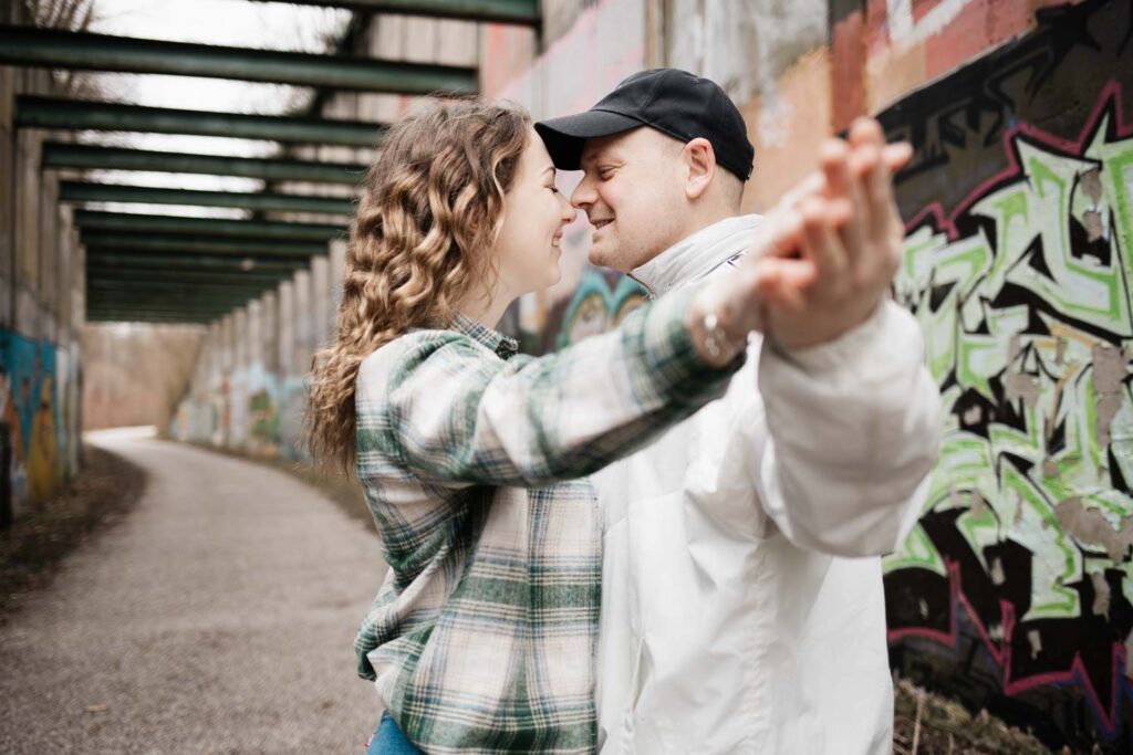 Paarshooting Phoenix West Dortmund Paar steht eng beieinander, strecken ihre Arme aus und lächeln dabei