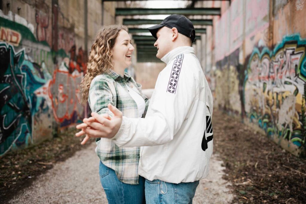 Paarshooting Phoenix West Dortmund Paar steht eng beieinander, strecken ihre Arme aus und lachen dabei