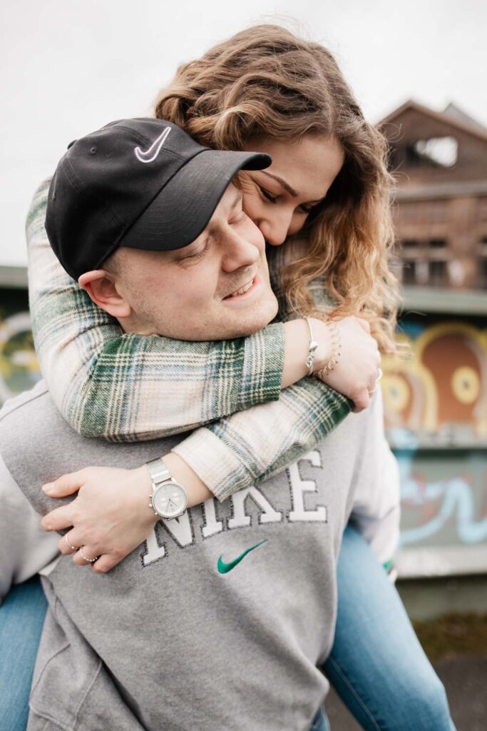 Paarshooting Phoenix West Dortmund Freund trägt Freundin Huckepack Freundin umarmt Freund fest